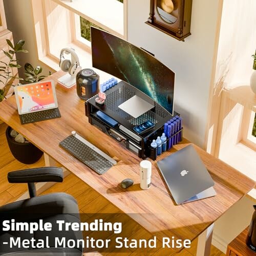 Modern desk setup with a metal monitor stand, laptop, keyboard, and tablet.