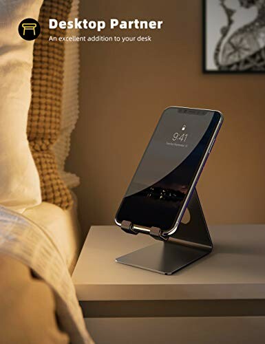 Smartphone on a sleek metal stand on a bedside table.