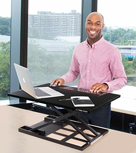 Man using a laptop on a standing desk in an office